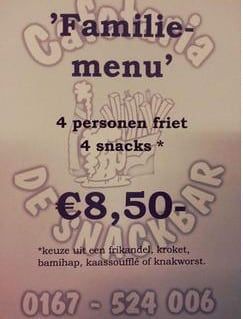 De echte familiemenu-poster die in Cafetaria de Snackbar hangt: 4 personen friet en 4 snacks voor 8,50 euro