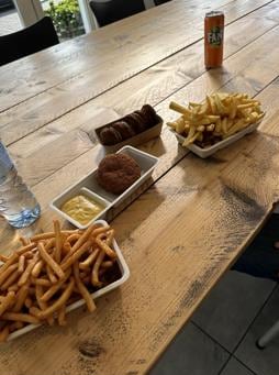 Friet met bitterballen en snacks op een houten tafel in de zaak